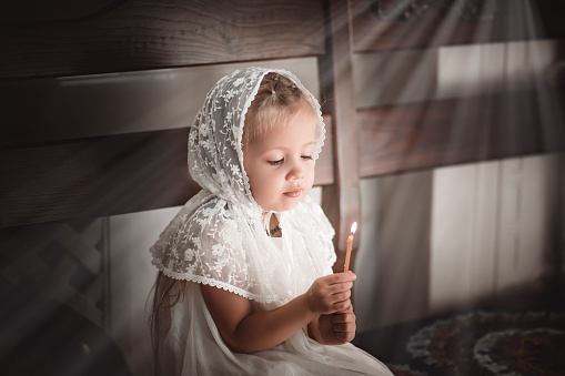 a little girl in a church or church with a candle in her hands prays to the icon or came to worship in the Russian Orthodox church