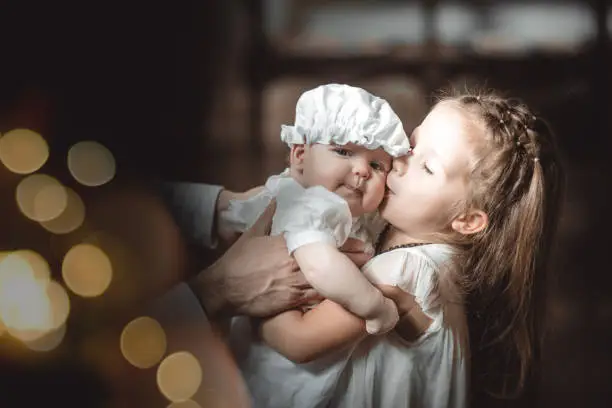 the elder sister kisses a baby in a baptismal outfit in a temple or church who came to worship in an Orthodox church or baptism a baby