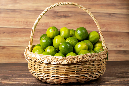 Lime lemon. Pile of lemons in basket on wood background