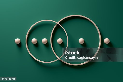 istock Crossing wooden rings with spheres in a row on green background. 1473133716