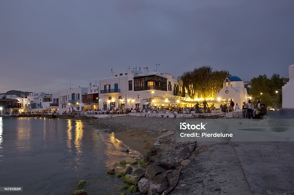 Mykonos beach at dusk People at restaurants on the beautiful beach of Mykonos at dusk, Greece Aegean Sea Stock Photo