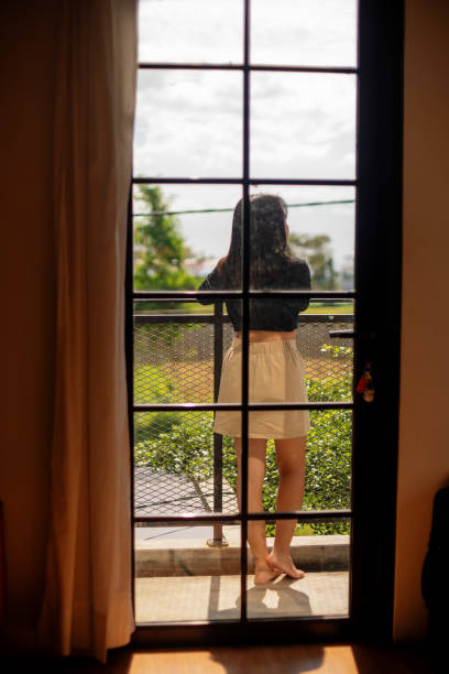 istock Asian Girl Standing Enjoying Mountain Scenery On a Balcony Framed Through Window 1473136554