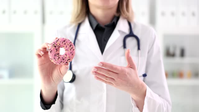 Doctor nutritionist showing sweet pink donut closeup 4k movie slow motion