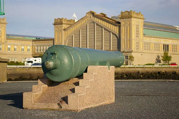 Cannon - monument, placed in Cherbourg, France. On the back, old railway station is seen.