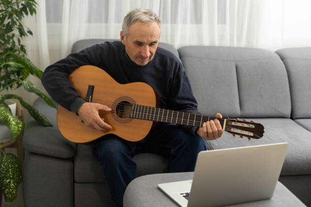 istock an elderly man learns to play the guitar on a laptop 1473144608