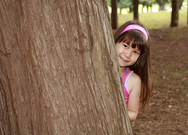 Garota esconder atrás de árvore - foto de acervo