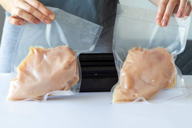 istock Vacuumed chicken fillet sous vide in front of a packaging machine in a woman's hands. 1473144726