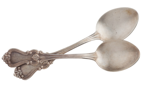 Two old silver spoons crossed isolated on white background