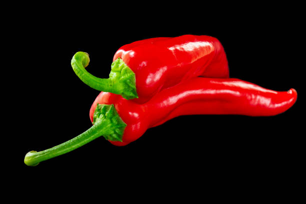 Red pepper. Several ripe red bell peppers on a black background, vegetables, sweet pepper