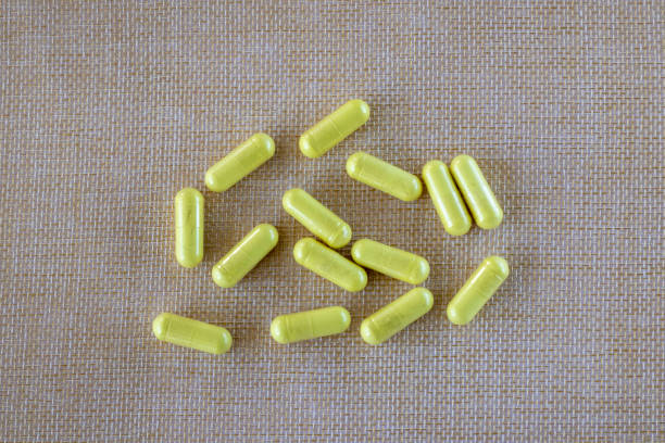 cápsulas de quercetina amarela em um fundo texturizado natural bege. suplemento dietético vista superior. é um flavonoide que tem efeitos anti-histamínicos e anti-inflamatórios em alergias, asma. - quercetin - fotografias e filmes do acervo