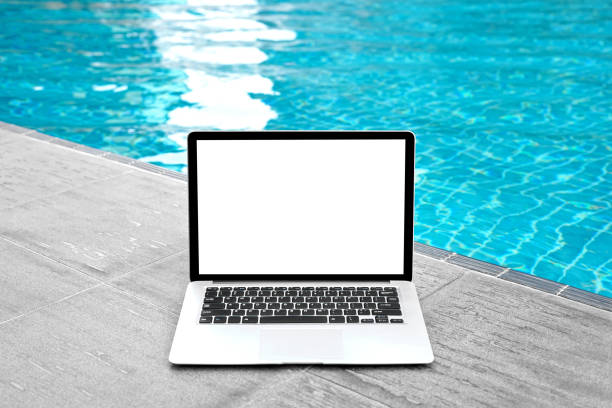 istock Laptop with blank screen for creative design on floor nearby swimming pool edge background. Computer notebook with monitor clipping path for present landing page design. Laptop computer mock up template 1473146242