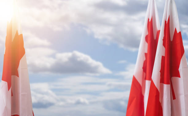 istock canadian flag against blue sky with white clouds. 1473146964