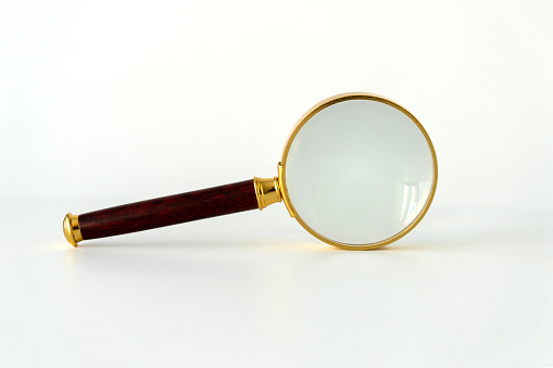 Golden magnifying glass on white background
