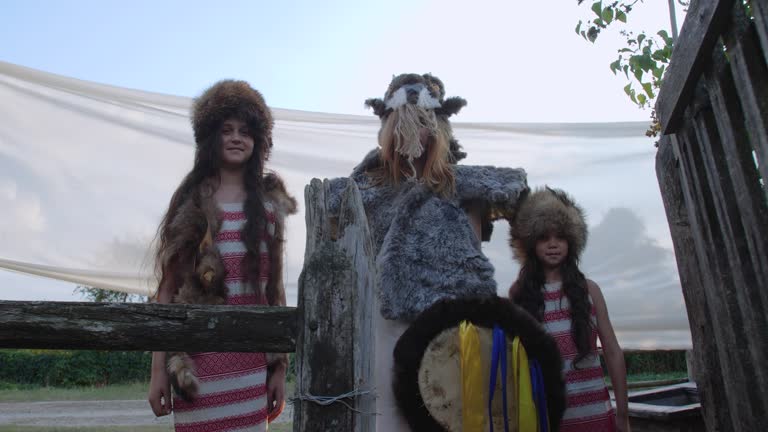 Group of three girls dressed in strange  fur suits, knocking on wooden door of rural house and throwing corn wishing wealth