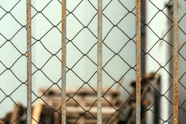 Chain link diamond pattern wire fence and worn metallic bars as background