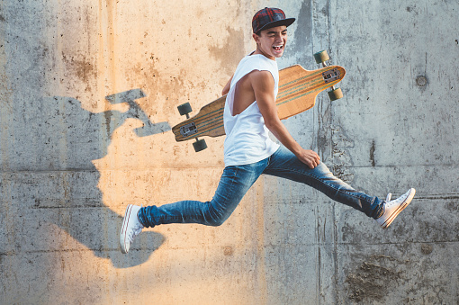 Skater Boy jumping with longboard.