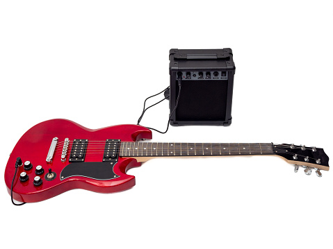 Red electric guitar and classic amplifier. Musical instrument guitar. Close-up.