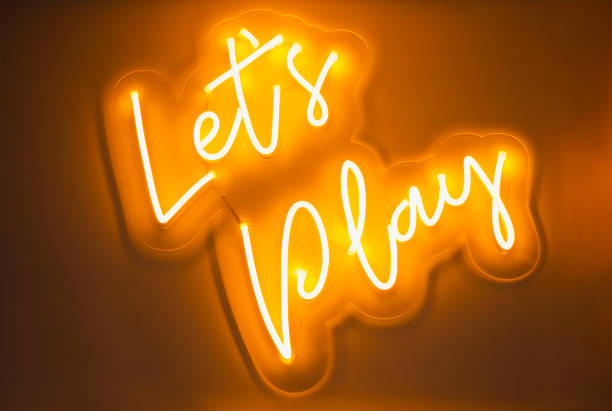 Let's Play Type font Neon sign light Signage on wall stock photo