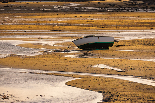 A small fishing boat stranded on a sandbank because of low tide. Colorful seascape.