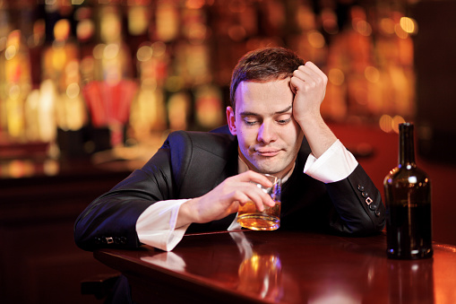 Young drunk man drinking whiskey in the bar
