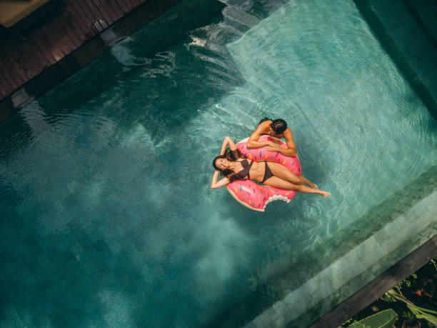 пара отдыхает на поплавке в бассейне курорта - swimming pool women floating on water bikini стоковые фото и изображения