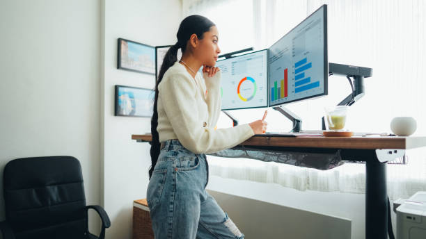 Woman with back pain working at standing desk home office stock photo
