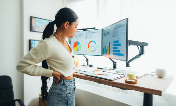istock Woman with back pain working at standing desk home office 1473164585