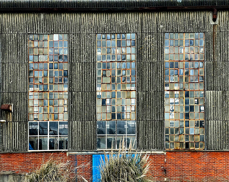 Rusty and broken windows in an old factory with corrugated walls