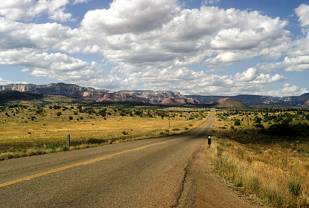 Long deserted road An empty road leading through Arizona, near Red Rock Canyon. hearkencreative stock pictures, royalty-free photos & images