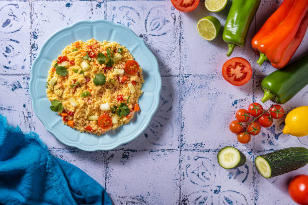 Tabouli, tabouleh salad recipe with tomatoes, pepper and cucumbers with ingredients on mediterranean white tiles table