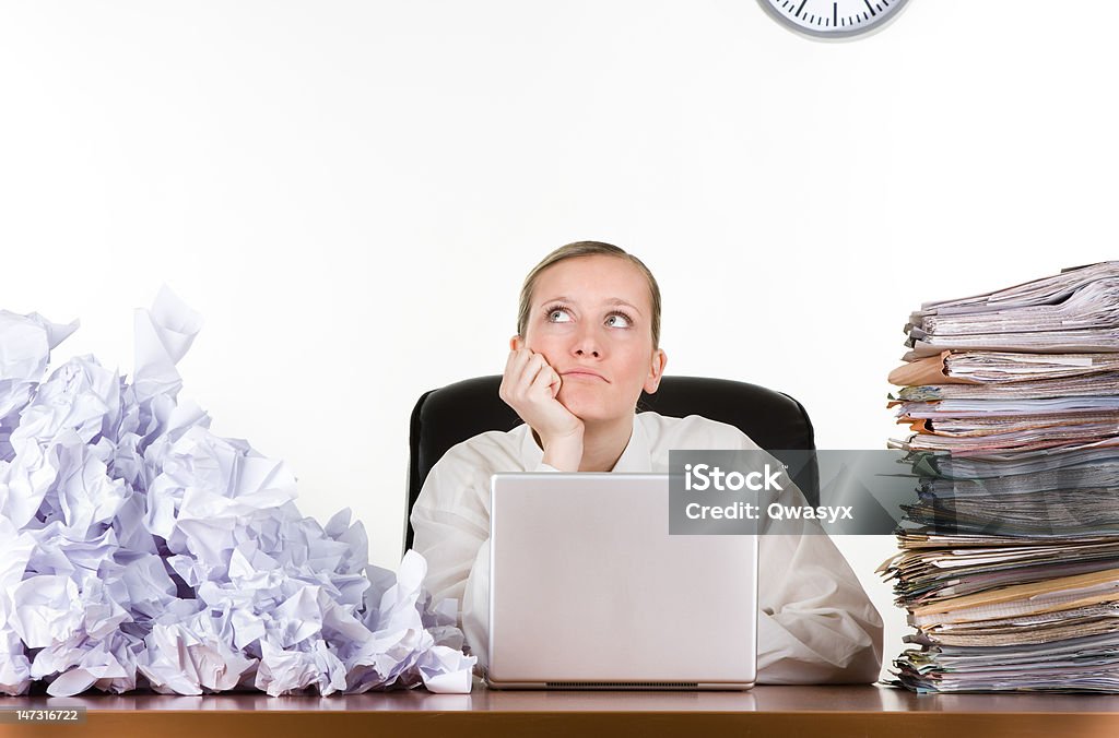 Businesswoman with paperwork Thinking businesswoman with stack of paperwork, pile of crumpled papers and a laptop computer. Drowning Stock Photo