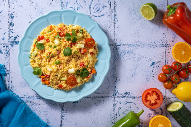 Tabouli, tabouleh salad recipe with tomatoes, pepper and cucumbers with ingredients on mediterranean white tiles table