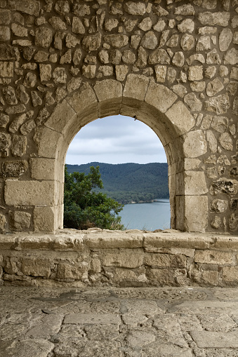 A window/arch at the entrance of a romanesque church in a spanish village (Castellet, Barcelona). A beautiful landscape may be seen through it.