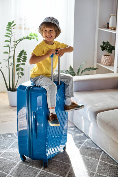 istock A child sitting on a suitcase have fun and laughs, waiting for a trip on vacation 1473167453