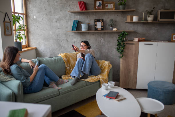 istock Two sisters using their phones and talking at home 1473171414