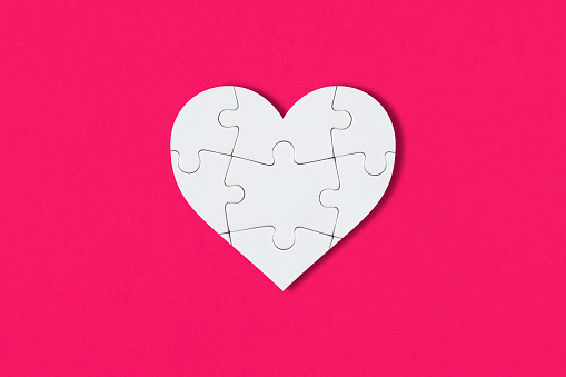 White puzzle pieces comes together as heart shape