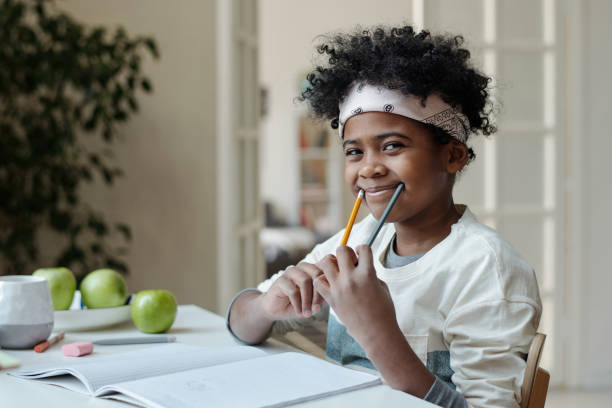 istock Cute schoolboy having fun while holding two pencils by edges of mouth 1473173582