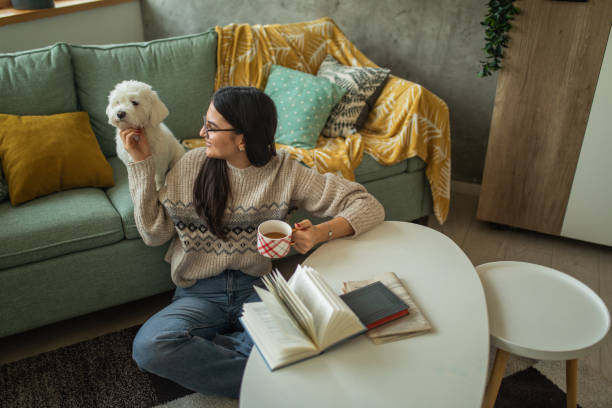 istock Young woman drinking tea while playing with her dog at home 1473173671