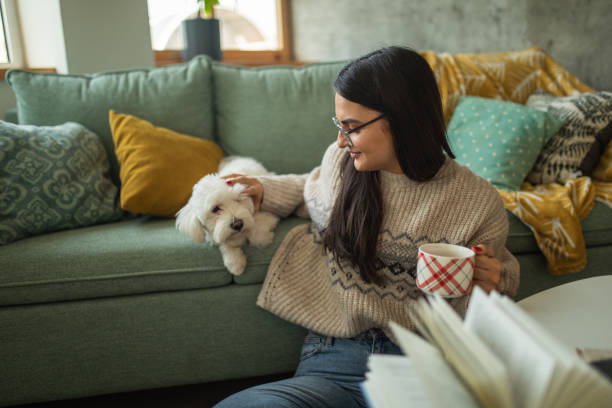 istock Young woman drinking tea while playing with her dog at home 1473173697