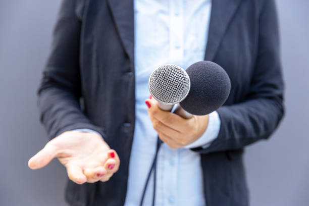 istock Female reporter gesturing during media interview, writing notes and holding microphone. Freedom of the press concept. 1473175263