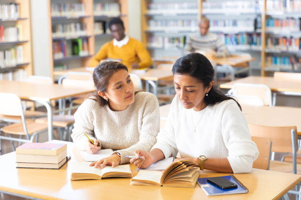 istock Two adult female students studying in university library 1473176157