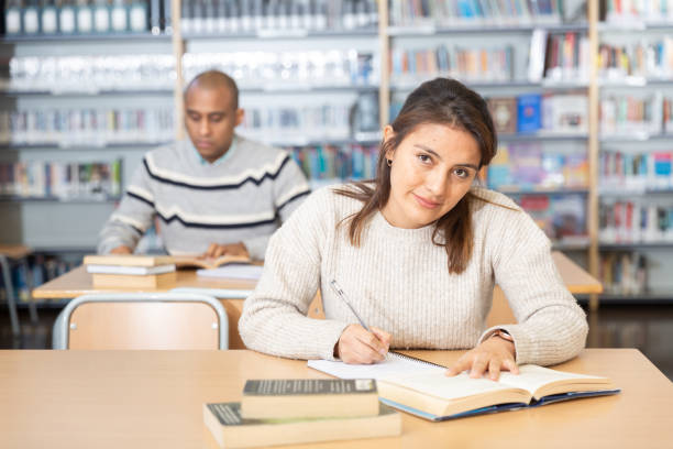 istock Positive young hispanic woman sitting in public library 1473176267