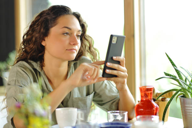 istock Woman checking smart phone in a restaurant 1473178398