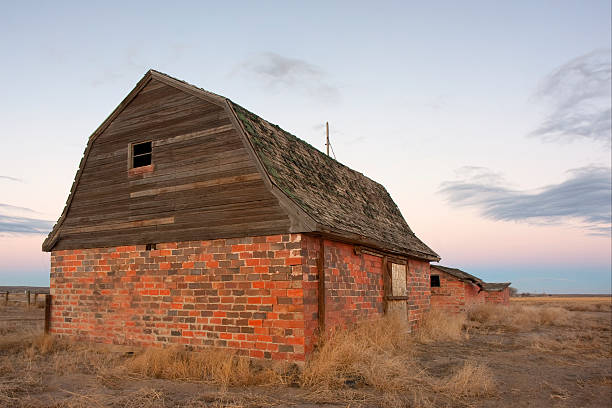 abandoned brick barn and farm buildings in eastern Colorado prairie at dusk