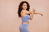Young curly sportswoman stretching arms
