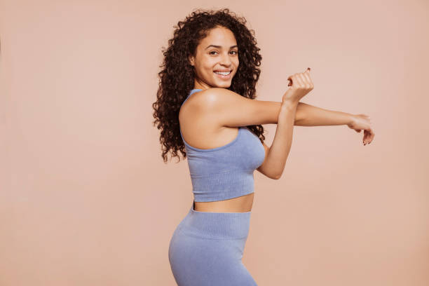 young curly sportswoman stretching arms - träningsutrustning sportutrustning bildbanksfoton och bilder
