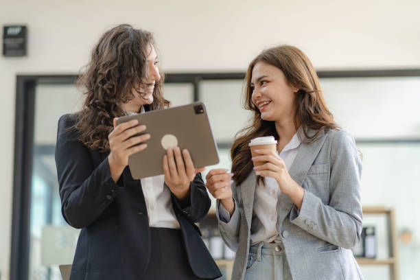 istock Two cheerful businesswoman working using digital tablet at conference table with documents working at office Business colleagues for real estate project discussion meeting 1473181559