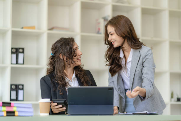istock Two cheerful businesswoman working using digital tablet at conference table with documents working at office Business colleagues for real estate project discussion meeting 1473181610