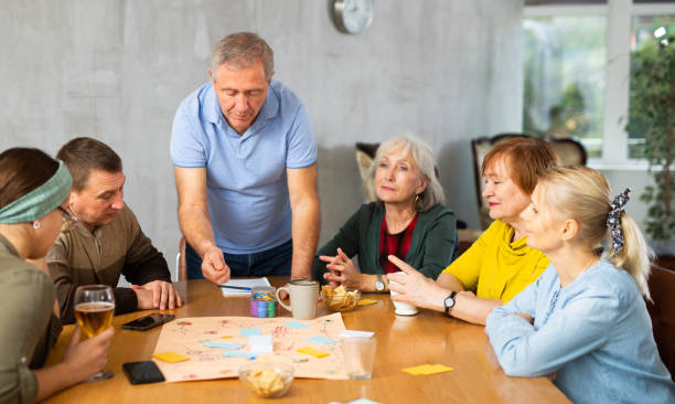 istock Group of happy mature people playing board game 1473181614