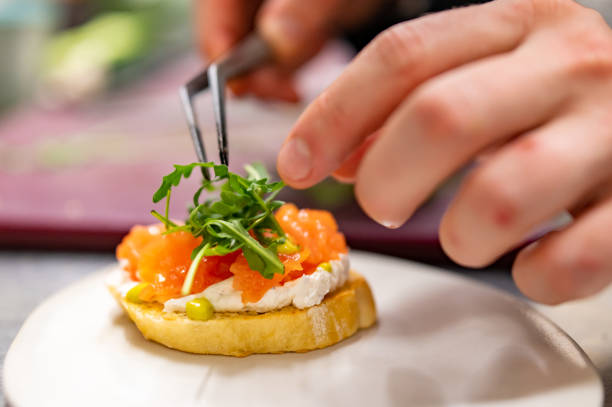 homme chef cuisinant à la main Bruschetta avec saumon et fromage à la crème dans la cuisine du restaurant - Photo